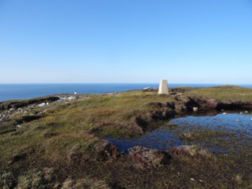 Trig point on Dùnan Mòr, lighthouse in background.